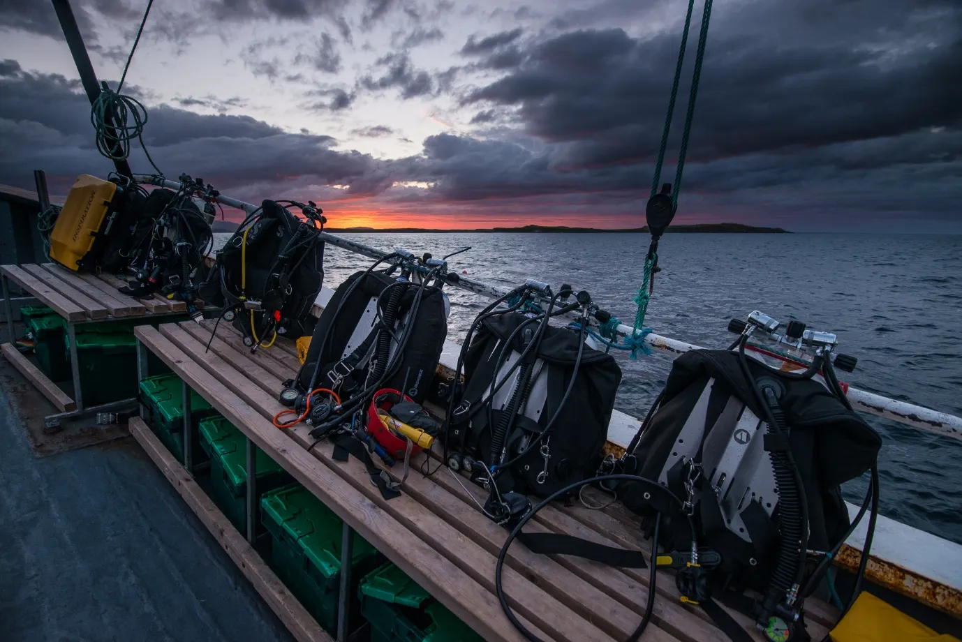 Dive gear lined up on a boat deck under a stormy evening sky